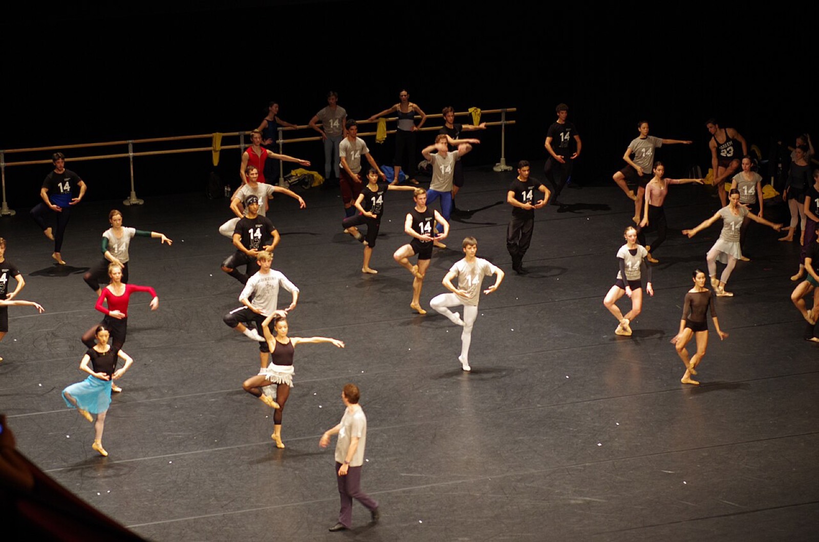 Compagnia di ballerini durante le prove su un palcoscenico teatrale.